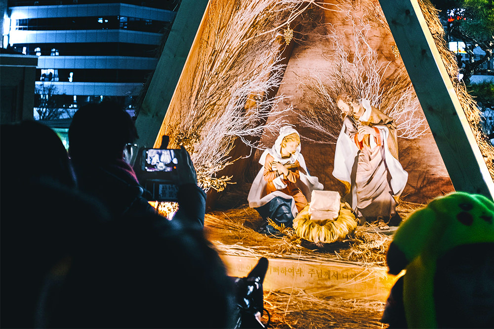 A man photographing a nativity scene in the Jung District of Seoul, South Korea